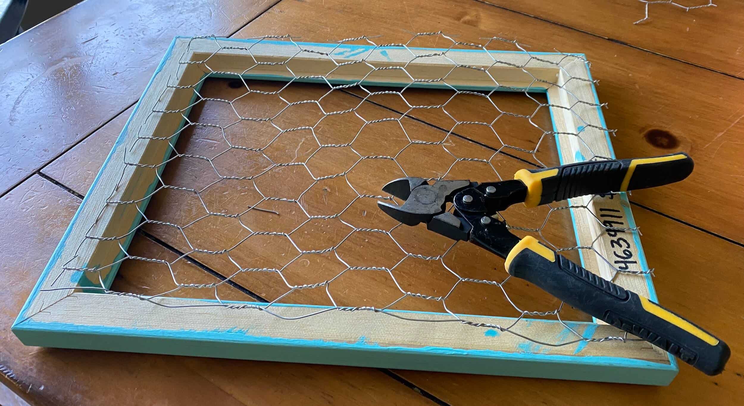 prep work of trimming chicken wire to size for Chicken Wire Memo Board