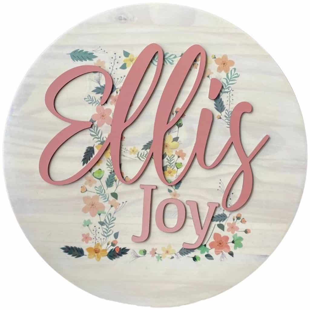 Wood round nursery sign for Ellis Joy with an image transferred to the wood in the background