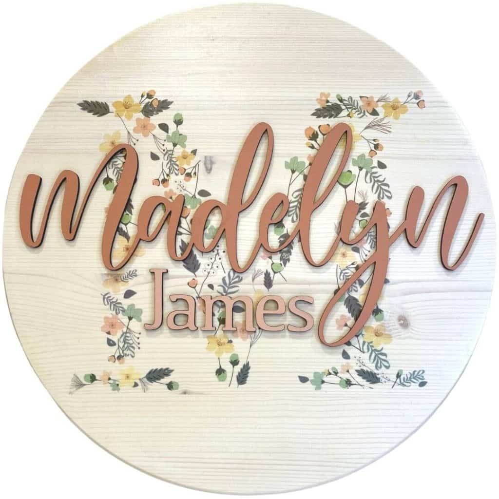 Wood round nursery sign for Madelyn James with an image transferred to the wood in the background